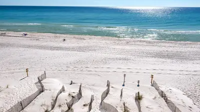 a sandy beach with a fence and the ocean at Leeward I Unit 8 in Santa Rosa Beach