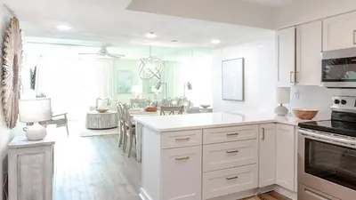 a kitchen with white cabinets and a dining room at Beachcrest 1005 in Santa Rosa Beach