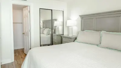 a white bedroom with a large bed and a mirror at Beachcrest 1005 in Santa Rosa Beach