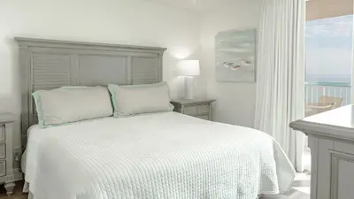 a white bedroom with a bed and a window at Beachcrest 1005 in Santa Rosa Beach