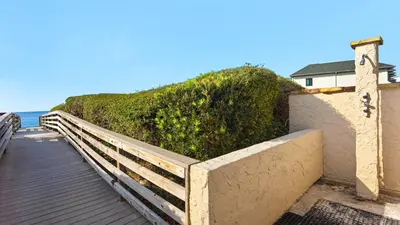 a wooden boardwalk next to a building and the ocean at Beachcrest 1002 in Santa Rosa Beach
