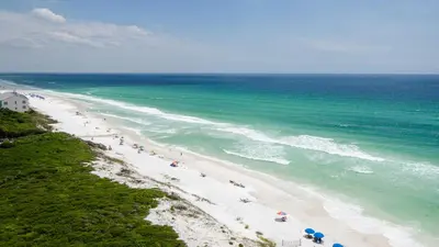 a beach with people and umbrellas and the ocean at Beachcrest 1002 in Santa Rosa Beach