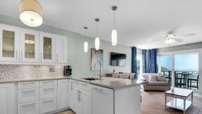 a kitchen with white cabinets and a living room at Mistral 1 Bare Feet Retreat in Seacrest