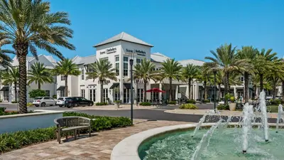 a fountain in front of a building with palm trees at Mistral 1 Bare Feet Retreat in Seacrest