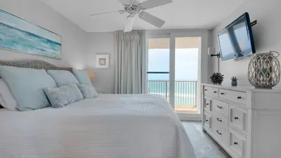 a bedroom with a bed with a television and a balcony at Beachcrest 1101 in Santa Rosa Beach