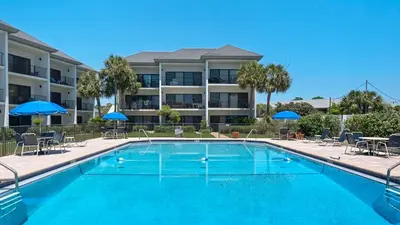 a pool with chairs and umbrellas in front of a building at Emerald Hill 12A in Santa Rosa Beach