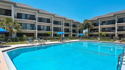a pool with chairs and umbrellas in front of a hotel at Emerald Hill 12A in Santa Rosa Beach