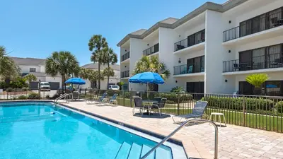 a swimming pool with chairs and umbrellas in front of a building at Emerald Hill 12A in Santa Rosa Beach