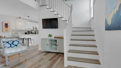 a white staircase in a living room with a table and a chair at Soul Shine in Santa Rosa Beach