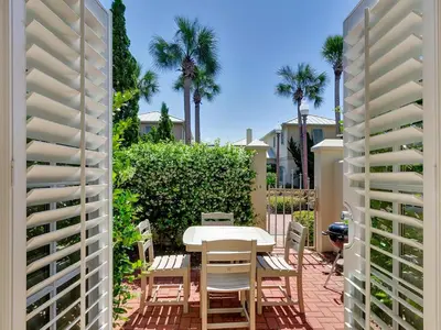 a patio with a table and chairs and palm trees at Mon Petit Chateau in Panama City Beach