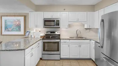 a kitchen with white cabinets and a stainless steel refrigerator at Beachcrest 1201 in Santa Rosa Beach