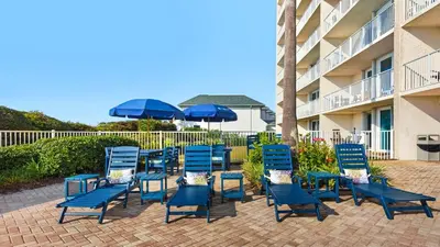a group of blue chairs and umbrellas next to a building at Beachcrest 1102 in Santa Rosa Beach