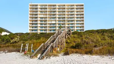 a building on the beach with a wooden staircase leading to the beach at Beachcrest 1102 in Santa Rosa Beach