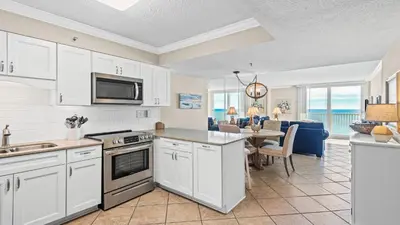 a kitchen with white cabinets and a dining room at Beachcrest 1102 in Santa Rosa Beach