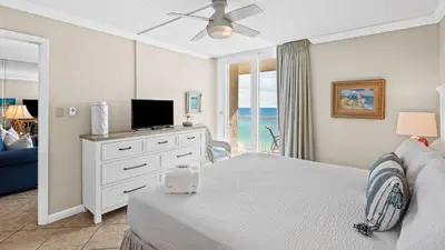 a white bedroom with a bed and a tv at Beachcrest 1102 in Santa Rosa Beach