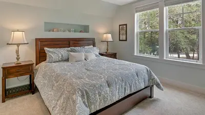 a bedroom with a bed and two windows at Blue Bungalow in Santa Rosa Beach