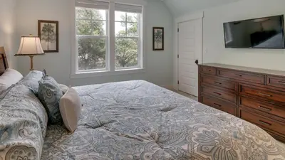 a bedroom with a bed with a dresser and a television at Blue Bungalow in Santa Rosa Beach