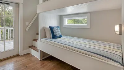 a small bedroom with a bed with a window at Blue Bungalow in Santa Rosa Beach