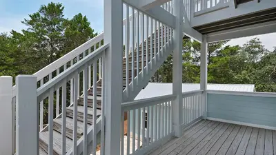 a white staircase on a house with a deck at Blue Bungalow in Santa Rosa Beach