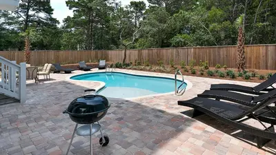 a swimming pool with a grill next to a fence at Blue Bungalow in Santa Rosa Beach
