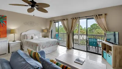 a bedroom with a bed and a tv and a balcony at Beachfront Condo II 202A - Out of the Blue in Santa Rosa Beach