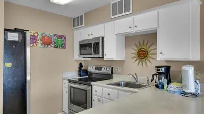 a kitchen with white cabinets and a sink at Beachfront Condo II 202A - Out of the Blue in Santa Rosa Beach