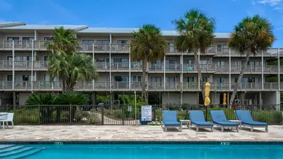 a hotel with palm trees and chairs in front of a pool at Beachfront Condo II 202A - Out of the Blue in Santa Rosa Beach