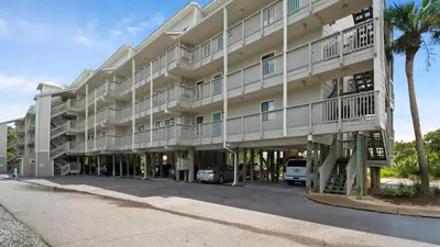 a large white building with palm trees in front of it at Beachfront Condo II 202A - Out of the Blue in Santa Rosa Beach