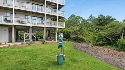 a building with a green lawn in front of it at Beachfront Condo II 202A - Out of the Blue in Santa Rosa Beach