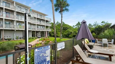 a hotel with a balcony with chairs and an umbrella at Beachfront Condo II 202A - Out of the Blue in Santa Rosa Beach