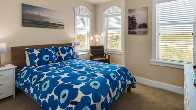 a bedroom with a blue and white bed and windows at Monterey Condos B302 in Panama City Beach