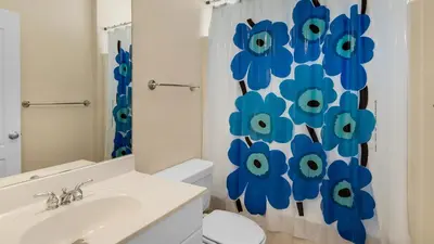 a bathroom with a toilet and a shower curtain with blue flowers at Monterey Condos B302 in Panama City Beach