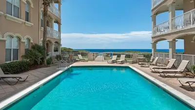 a swimming pool next to a building with chairs at Monterey Condos B302 in Panama City Beach