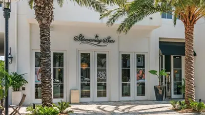a white building with palm trees in front of it at Blue Nine 9 in Panama City Beach