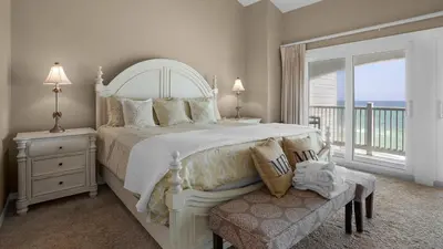 a white bedroom with a large bed and a balcony at Blue Tide 3B in Panama City Beach