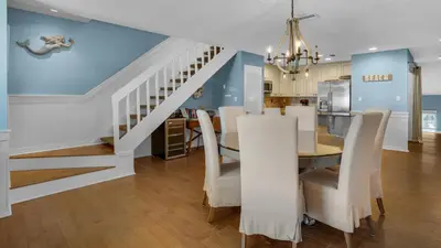 a dining room and kitchen with a dining table and stairs at Blue Tide 3B in Panama City Beach