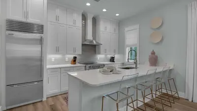 a white kitchen with white cabinets and a large island at Resting Beach Face in Rosemary Beach