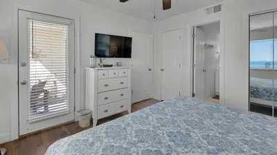 a white bedroom with a bed and a television at Beachside Condo 1 in Santa Rosa Beach