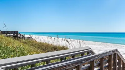 a wooden staircase leading to a beach with the ocean at Beachside Condo 1 in Santa Rosa Beach