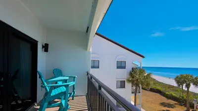 a balcony with two blue chairs and the beach at Palms A12 in Santa Rosa Beach