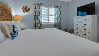 a bedroom with a large white bed and a dresser at Palms A12 in Santa Rosa Beach