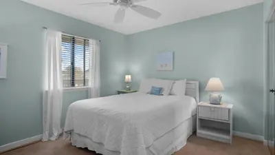 a white bedroom with a bed and a window at Beachside Condo 11 in Santa Rosa Beach