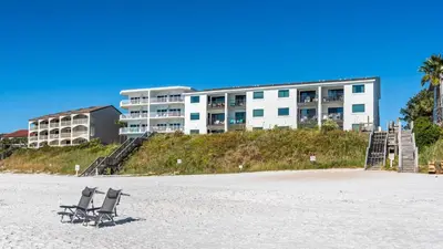 two chairs sitting on the beach in front of a building at Beachside Condo 11 in Santa Rosa Beach