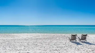 two chairs sitting on a beach next to the ocean at Beachside Condo 11 in Santa Rosa Beach