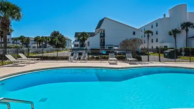 a swimming pool with chairs and a building at Beachside Condo 13 in Santa Rosa Beach