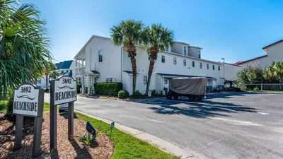 a street with palm trees and a house with a sign at Beachside Condo 14 in Santa Rosa Beach
