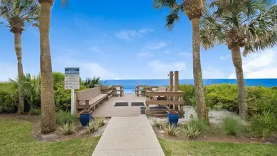 a pathway with benches and palm trees and the ocean at Palms C4 in Santa Rosa Beach