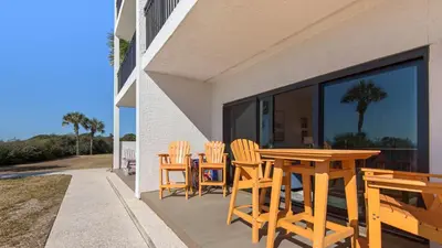 a wooden table and chairs on a patio at Palms C4 in Santa Rosa Beach