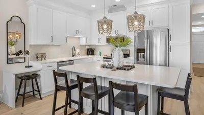 a kitchen with white cabinets and a large island with bar stools at Palms C7 in Santa Rosa Beach