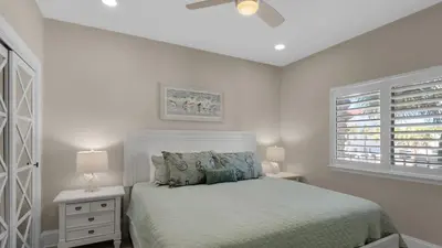 a white bedroom with a bed and two lamps at Palms C7 in Santa Rosa Beach